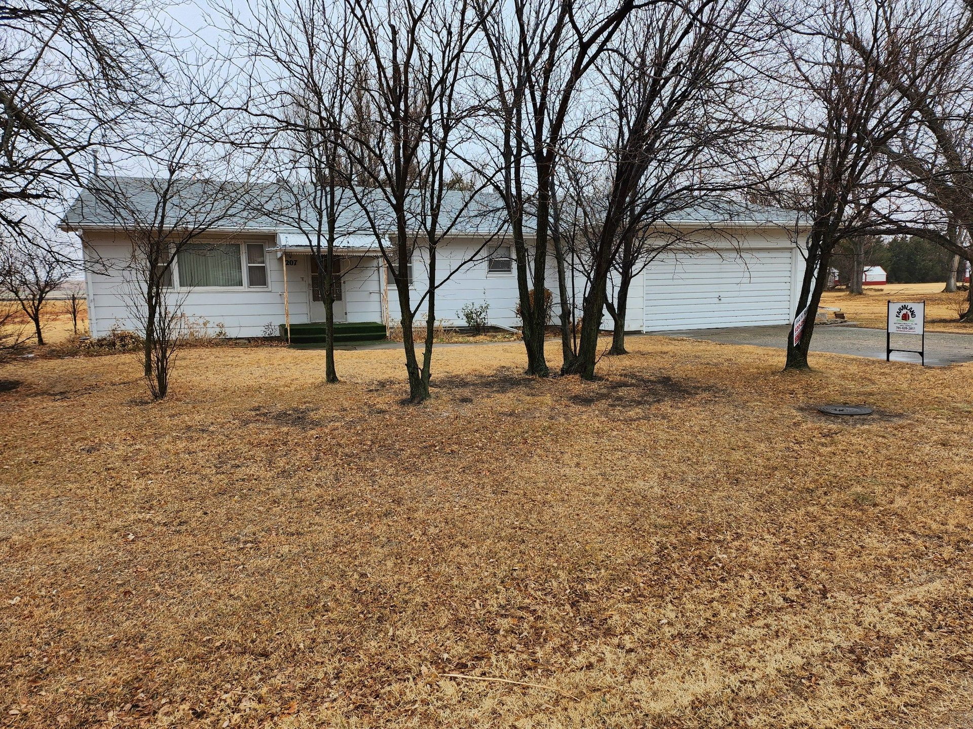 A house with a lot of leaves on the ground and trees in front of it.