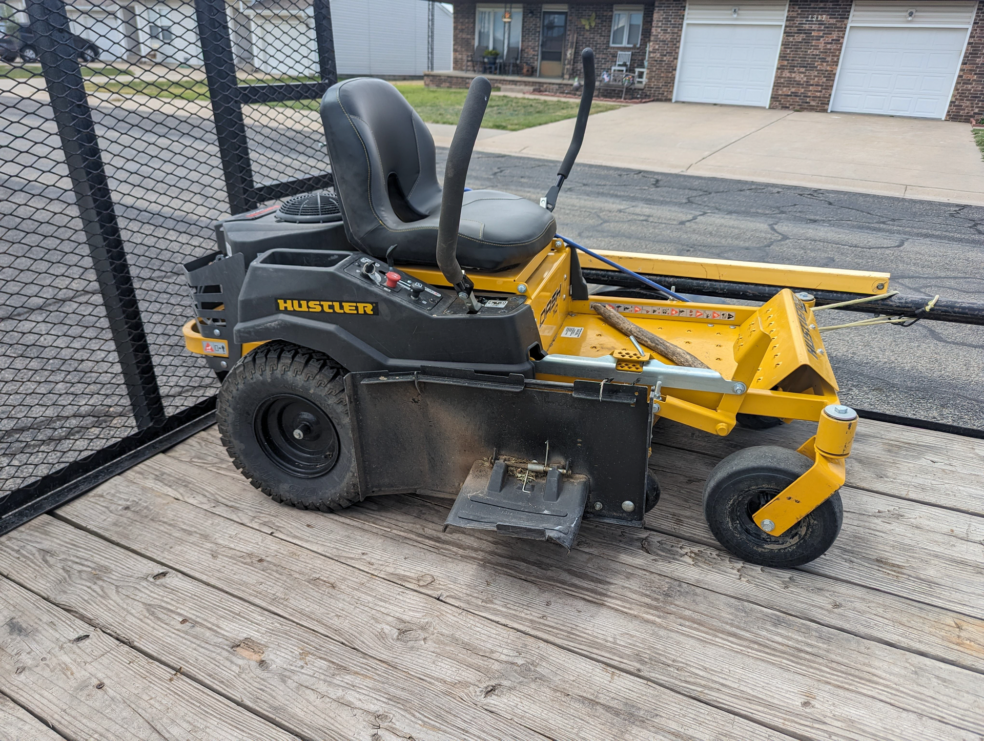A yellow and black lawn mower is parked on a wooden deck.