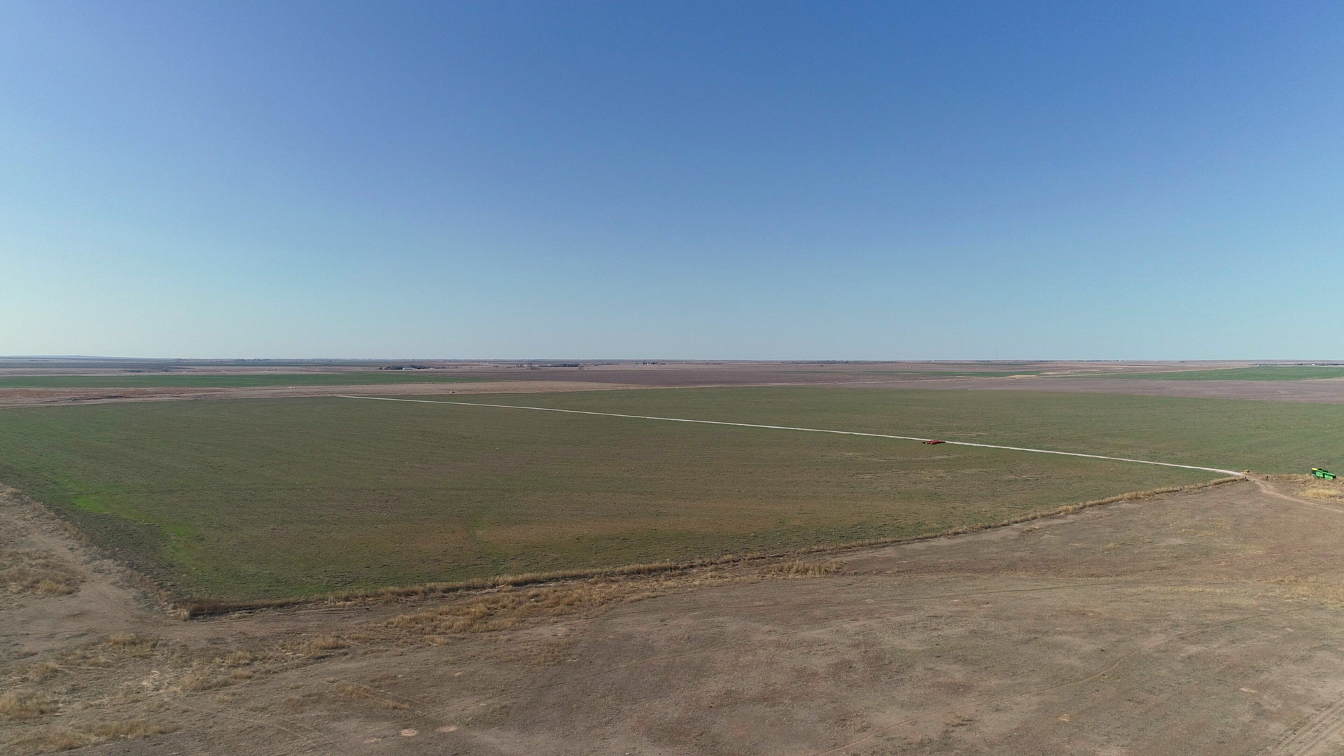 An aerial view of a large grassy field with a blue sky in the background.