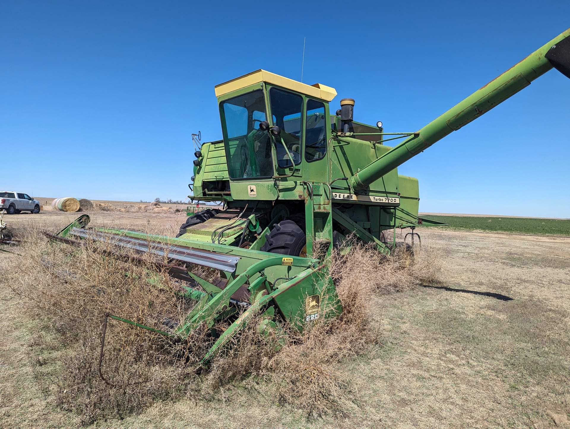 A green combine harvester is cutting grass in a field.