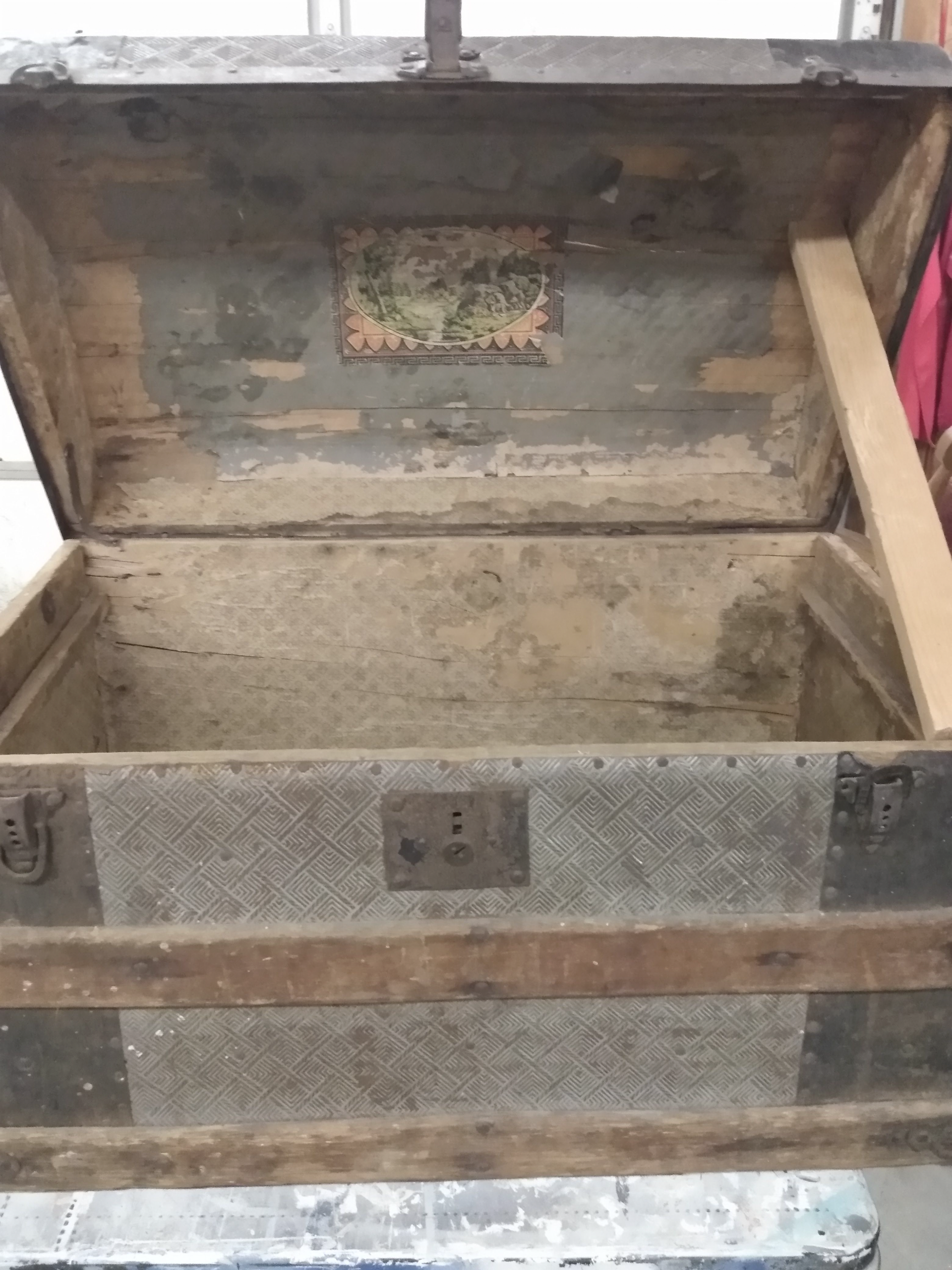 An old wooden trunk with the lid open is sitting on a table.