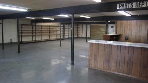 An empty room with a wooden counter and a sign that says parts department