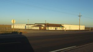 A large white building is sitting on the side of a road.