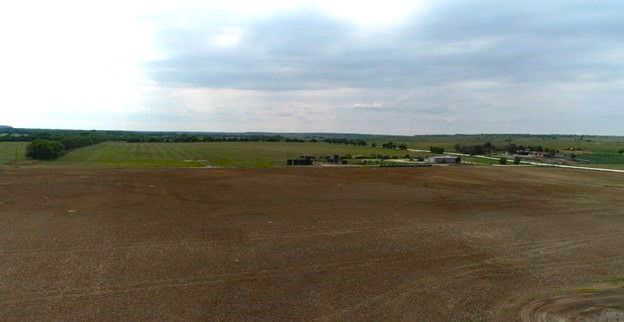A large brown field with a cloudy sky in the background