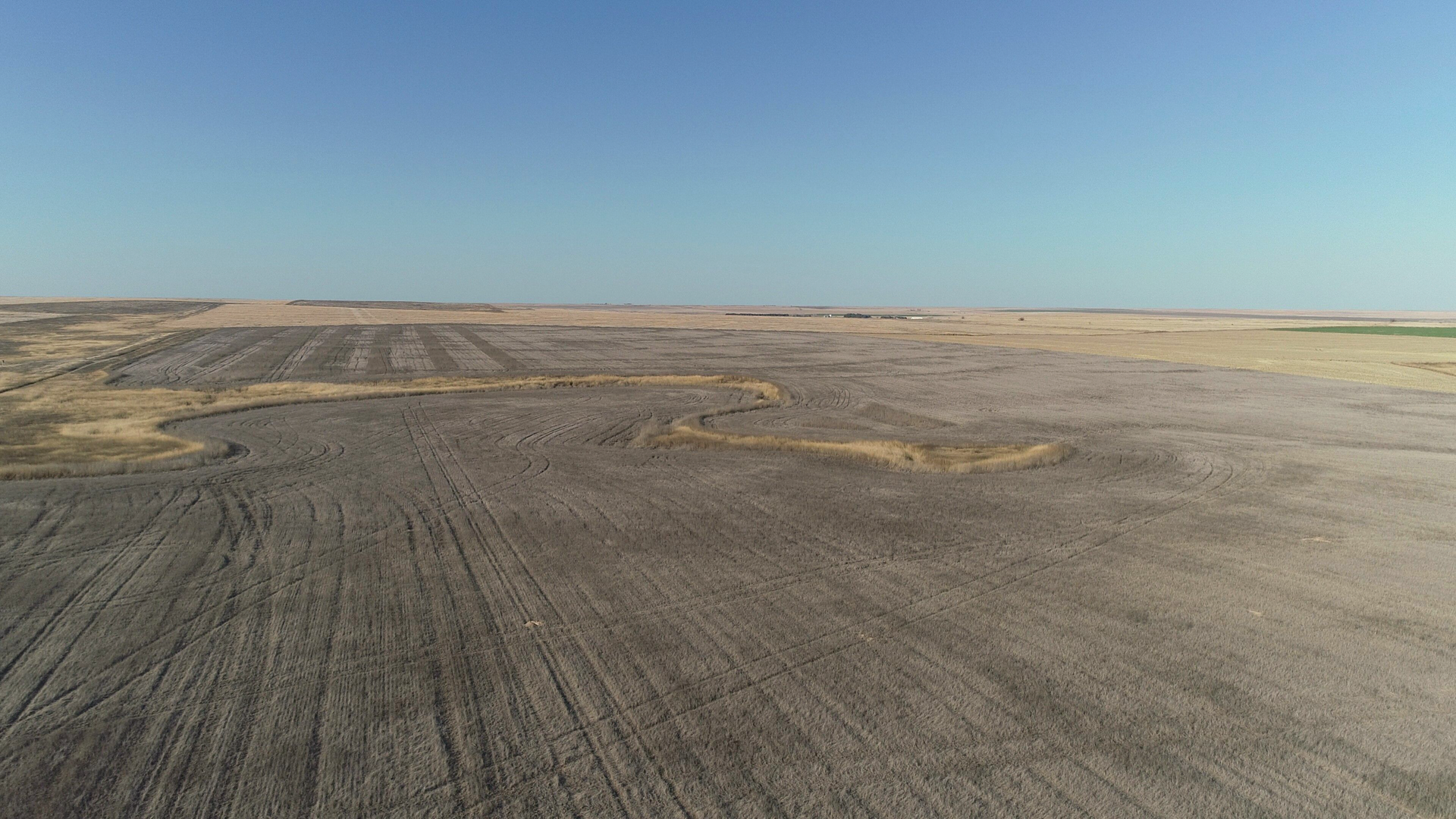An aerial view of a dirt field with a blue sky in the background.