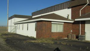 A brick building with a white roof is sitting in the middle of a field.