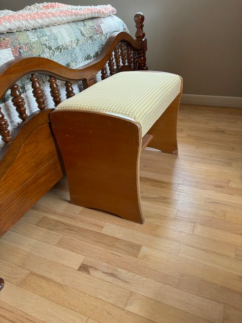 A wooden bench sits next to a bed in a bedroom