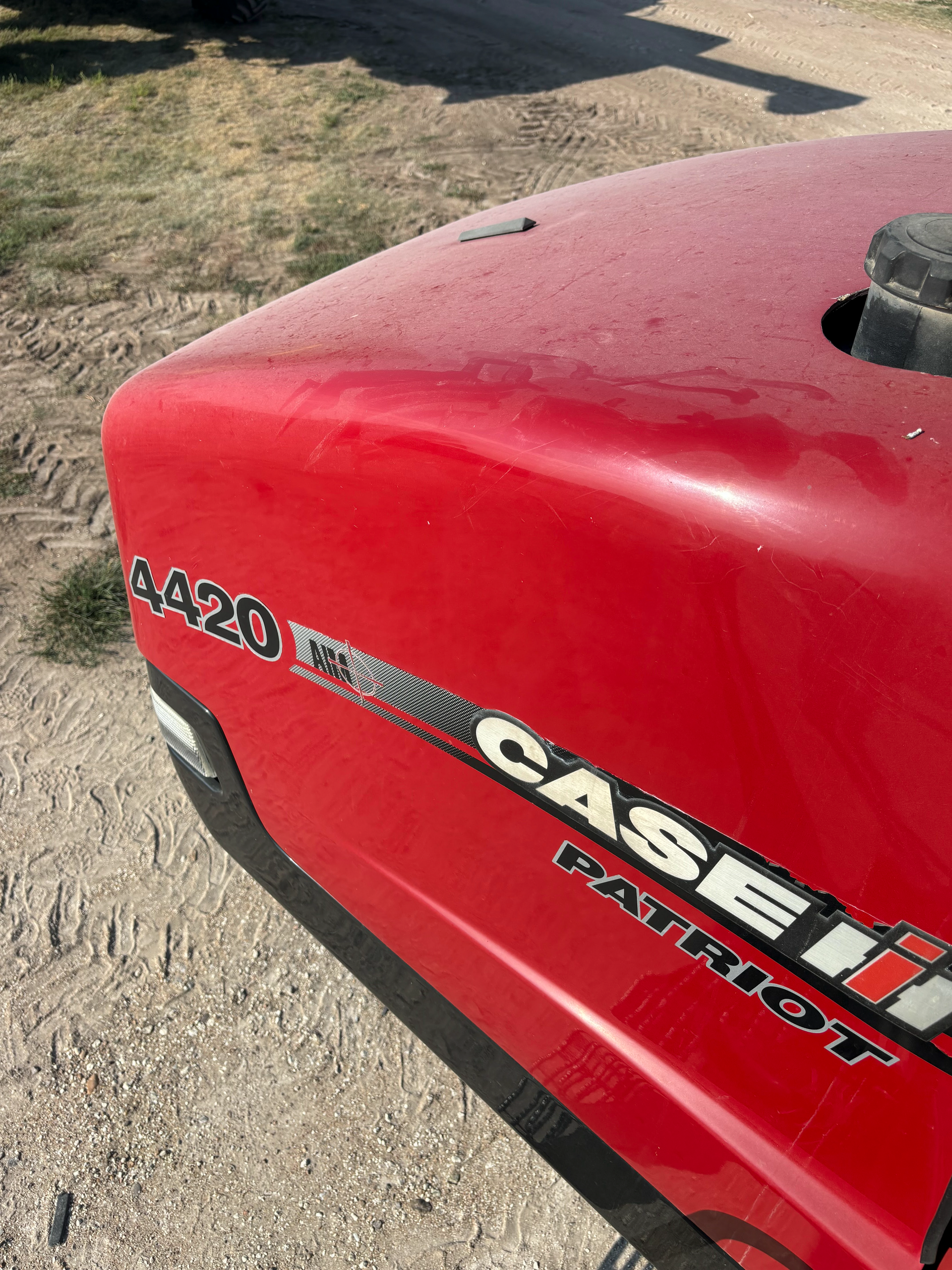 A red case ih patriot tractor is parked on a dirt road.