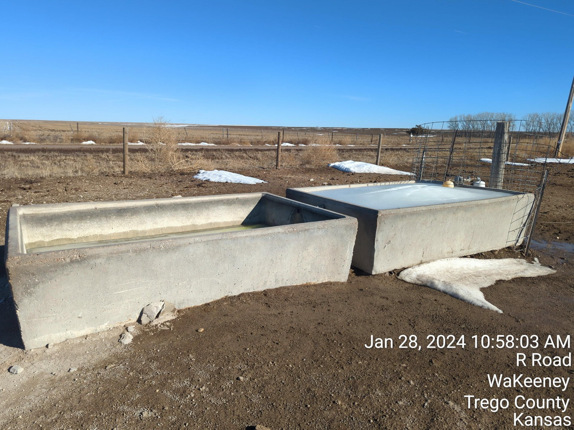 A concrete water trough in the middle of a field
