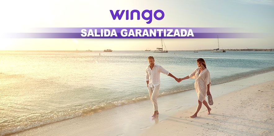 Un hombre y una mujer caminan por la playa tomados de la mano.
