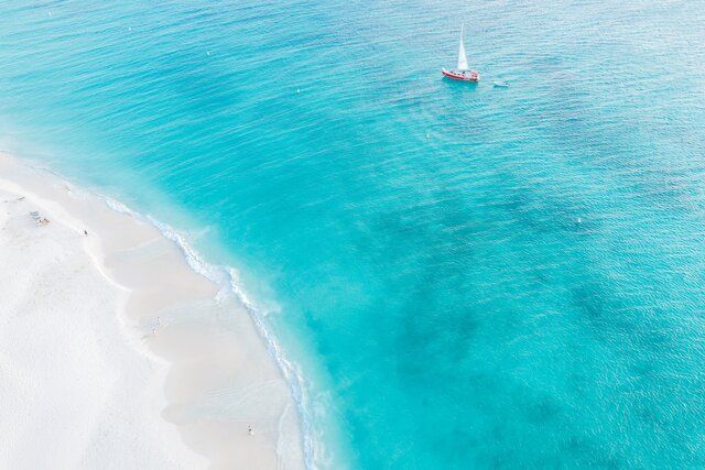 Una vista aérea de un velero en el océano cerca de una playa.