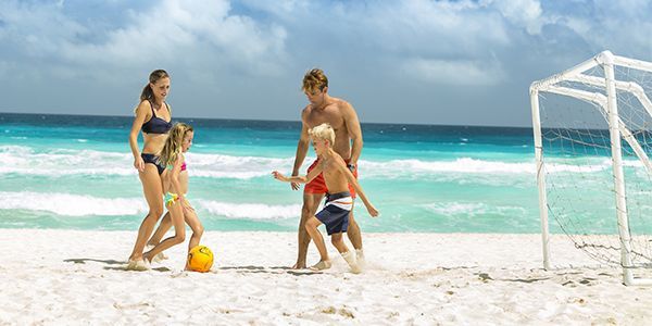 Una familia juega fútbol en la playa.