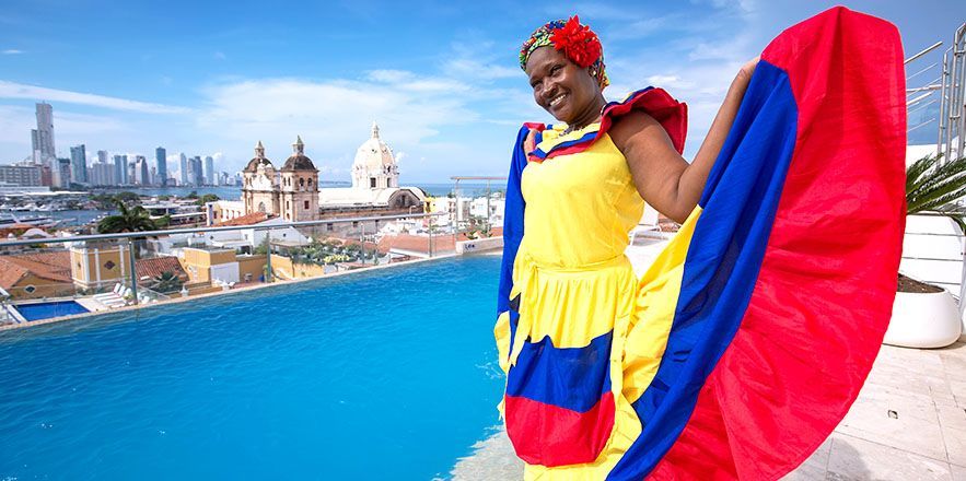 Una mujer con un vestido colorido está parada junto a una piscina.