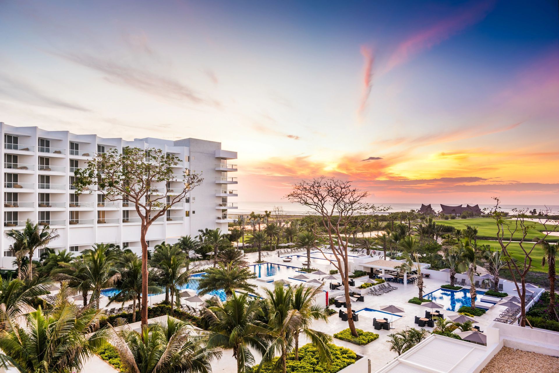 Una vista aérea de un resort con una puesta de sol al fondo.
