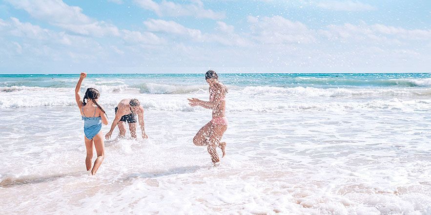 Un grupo de personas está jugando en el océano en una playa.