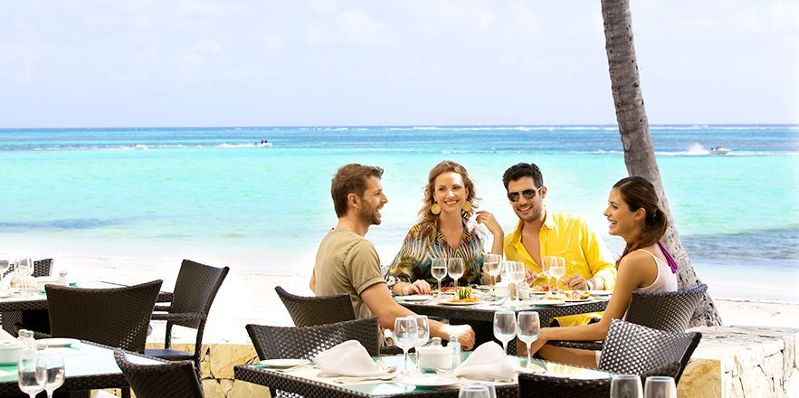 Un grupo de personas está sentada en una mesa en la playa.