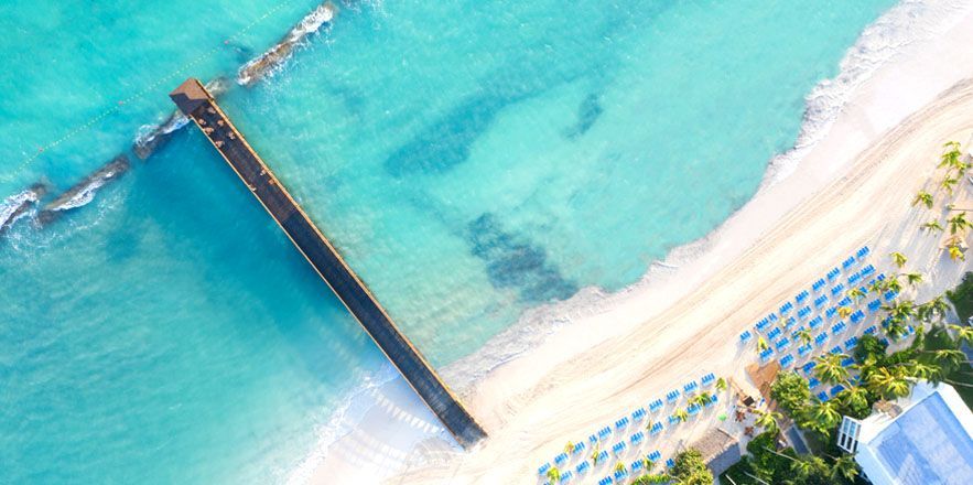 Una vista aérea de una playa con muelle y sombrillas.