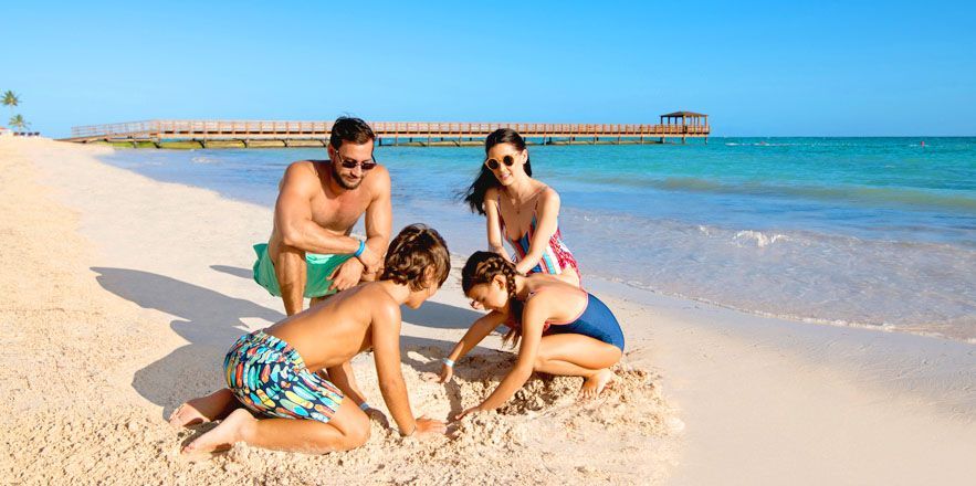 Una familia juega en la arena de la playa.