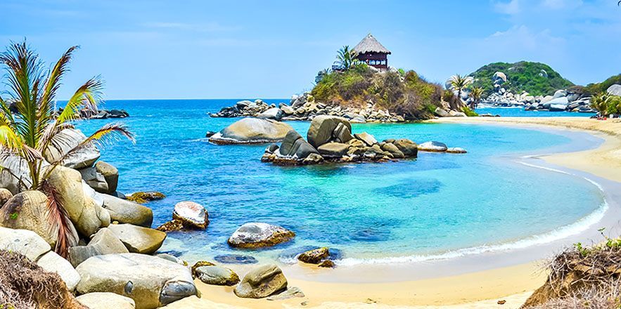 Una playa tropical con una pequeña isla en medio del océano.