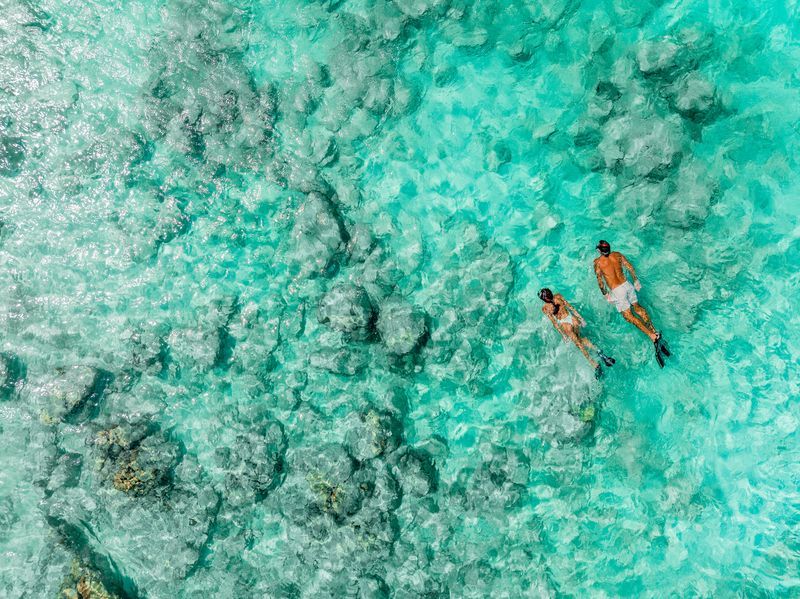 Un hombre y una mujer caminan por la playa tomados de la mano.