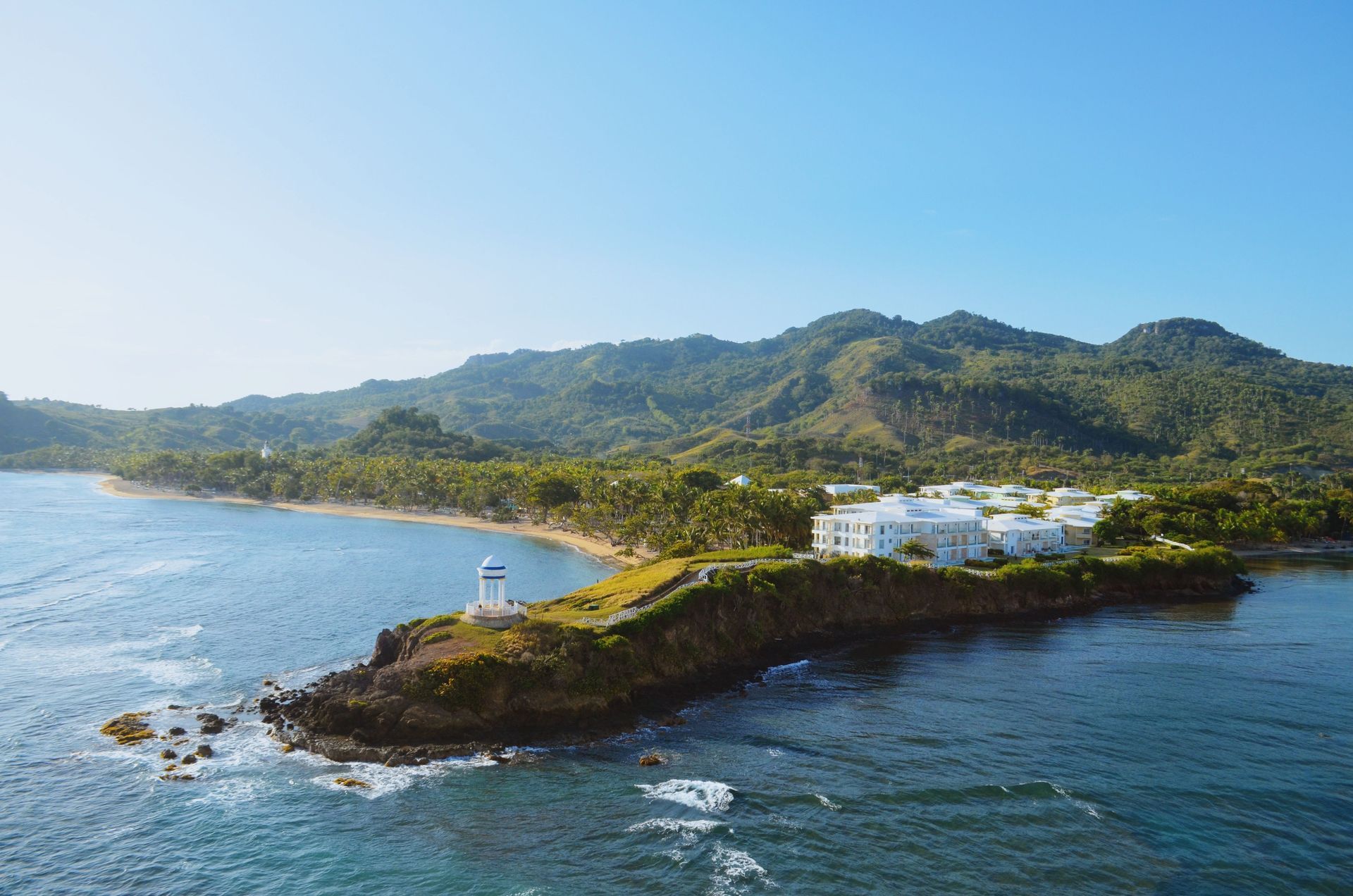 Un hombre y una mujer caminan por una playa con palmeras.