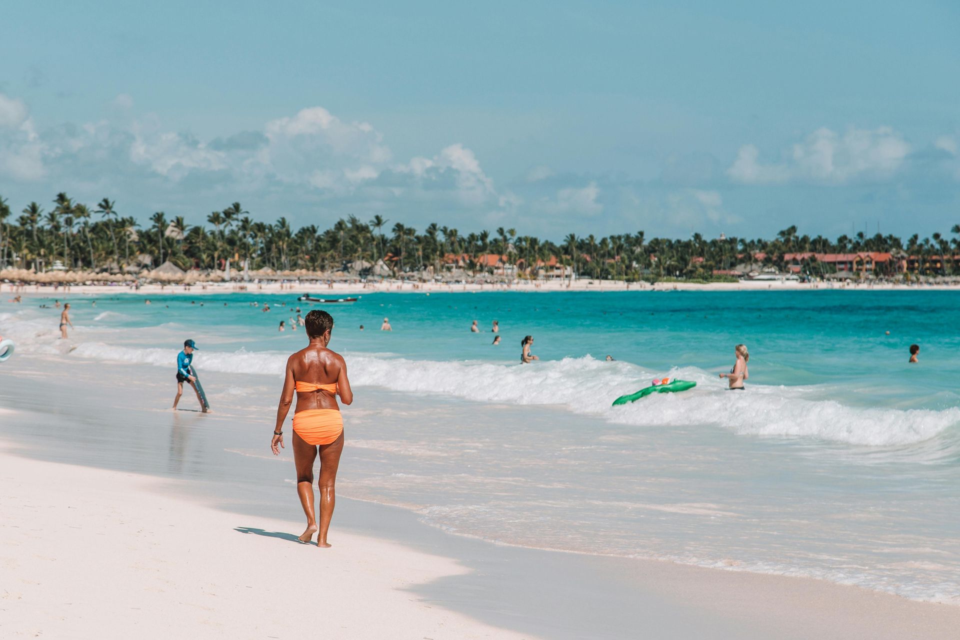 Un hombre y una mujer caminan por una playa con palmeras.
