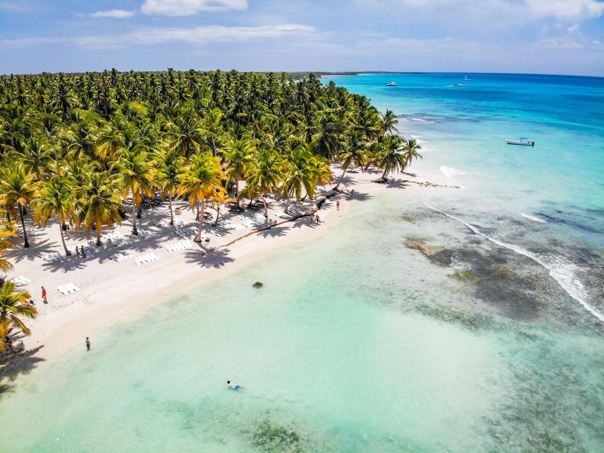 Un hombre y una mujer caminan por la playa tomados de la mano.