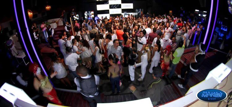 Una gran multitud de personas baila en una sala con un cartel que dice 'sáhara'