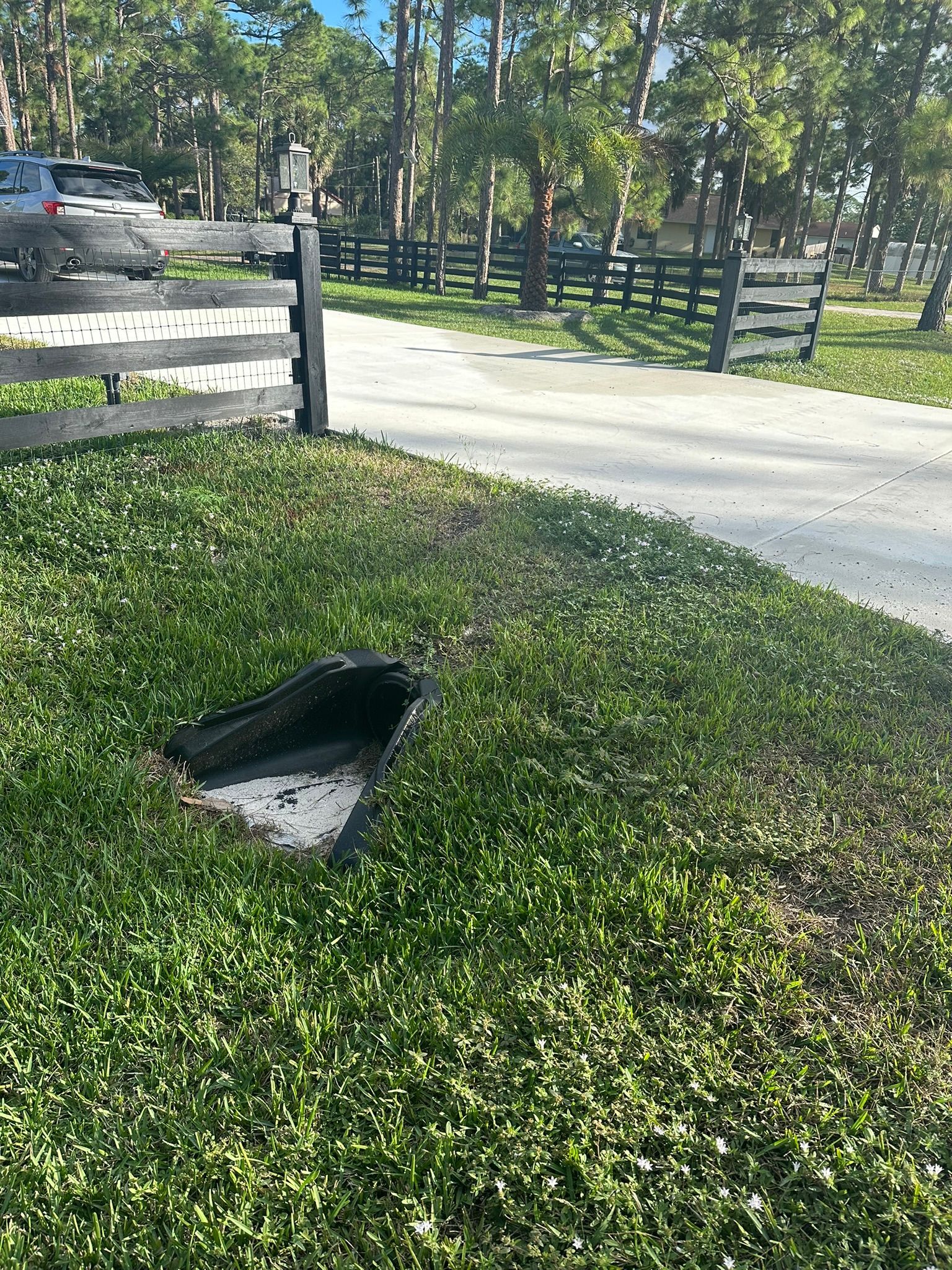 There is a hole in the grass next to a fence.