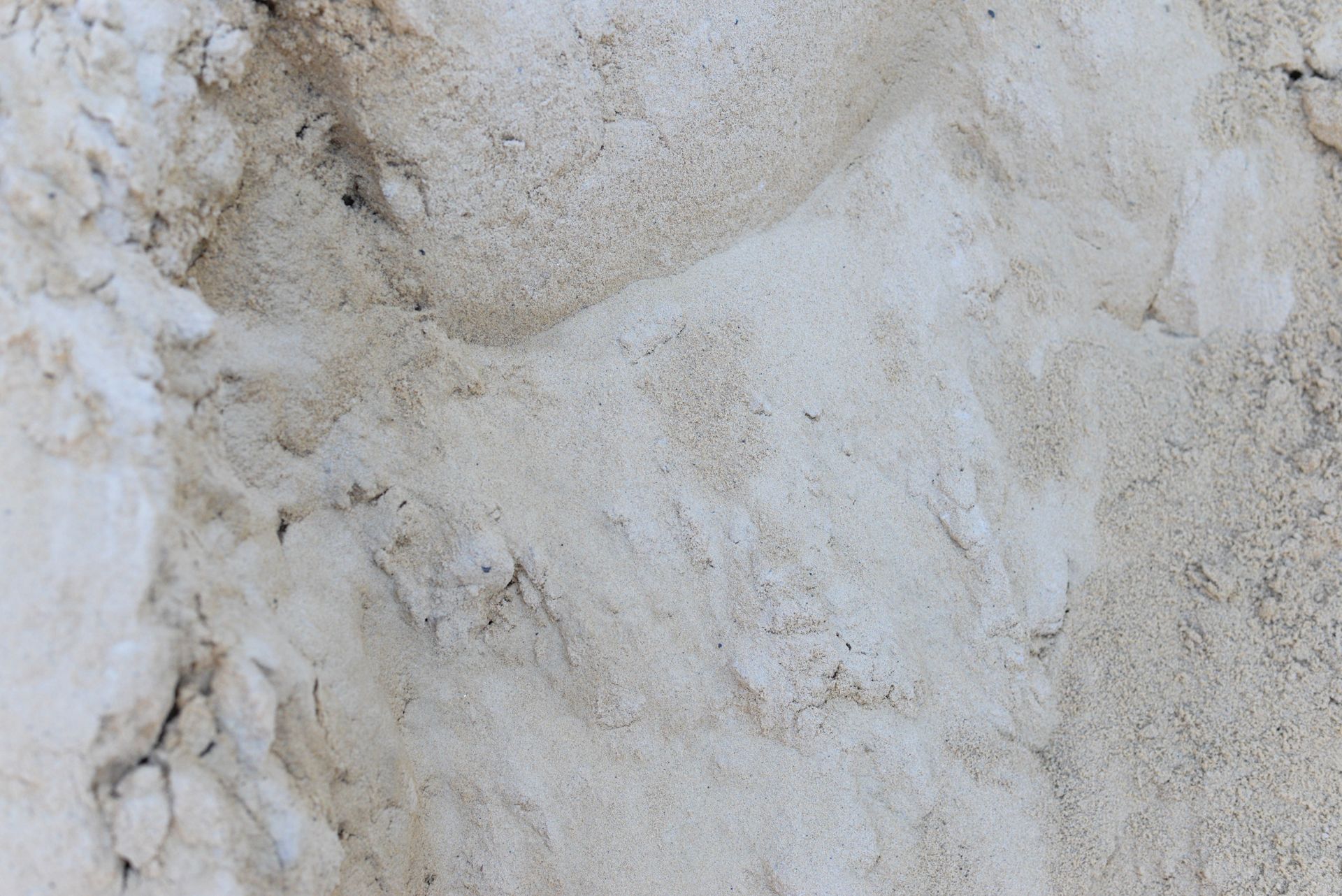 Close-up of light-colored sand with subtle variations in texture and tone.