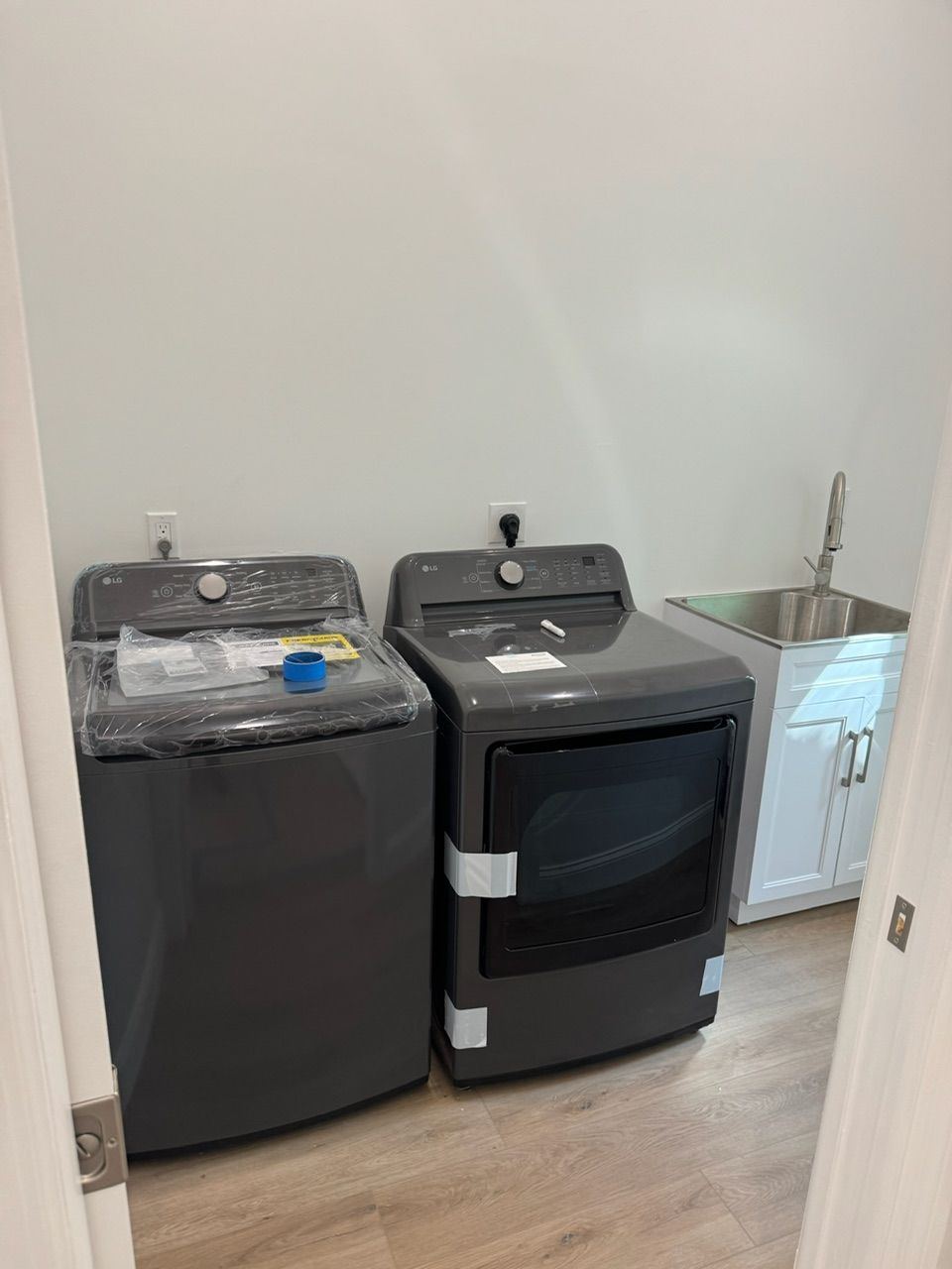 Laundry room with a gray washer and dryer, plus a sink with a cabinet.
