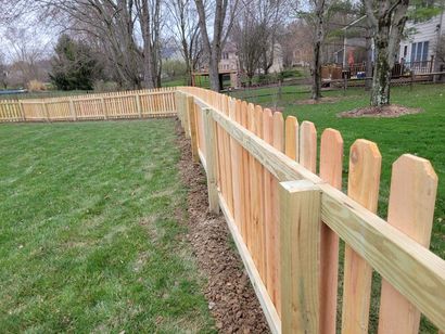New wooden picket fence along a grassy yard in a suburban neighborhood