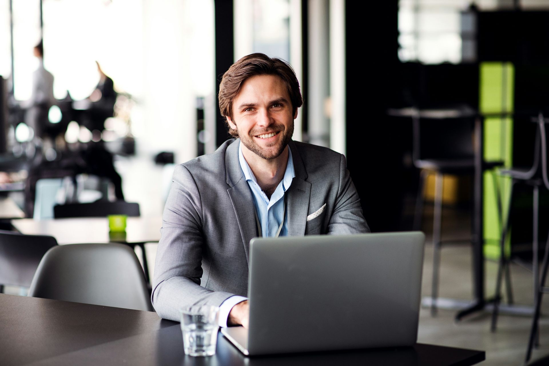 A man is sitting at a table using a laptop computer.