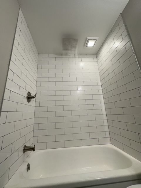 A bathroom with white brick walls and a bathtub