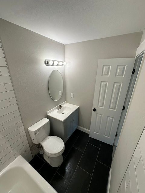 A bathroom with a toilet , sink and mirror