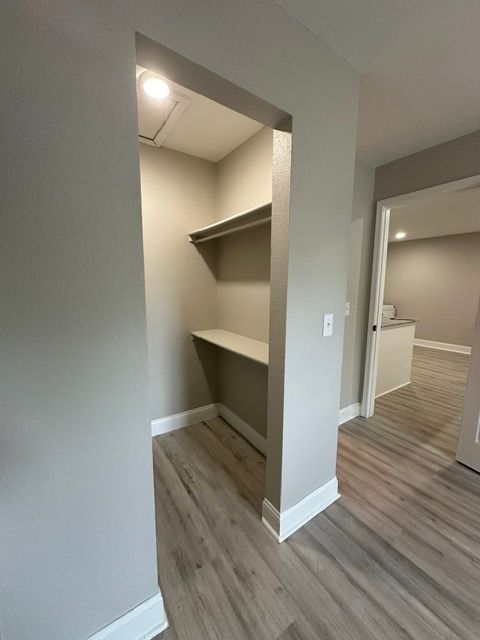 A walk in closet with a desk and shelves in a house.