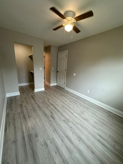 An empty room with hardwood floors and a ceiling fan.