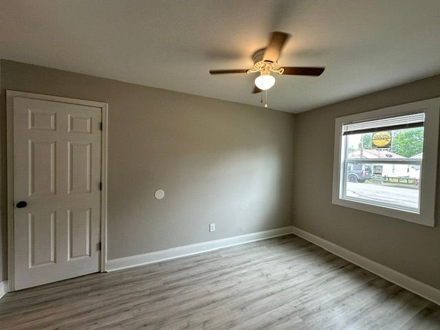 An empty bedroom with a ceiling fan and a window.