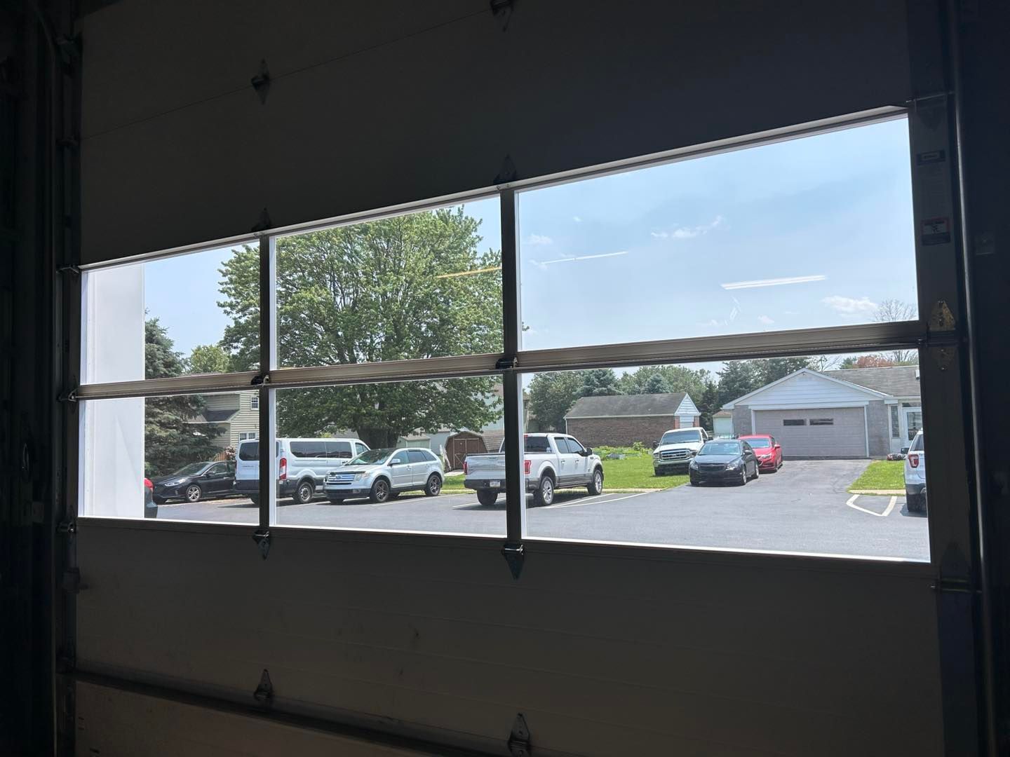 A central glass door framed in silver aluminum, flanked by frosted glass panels, in an office space with carpeted flooring.