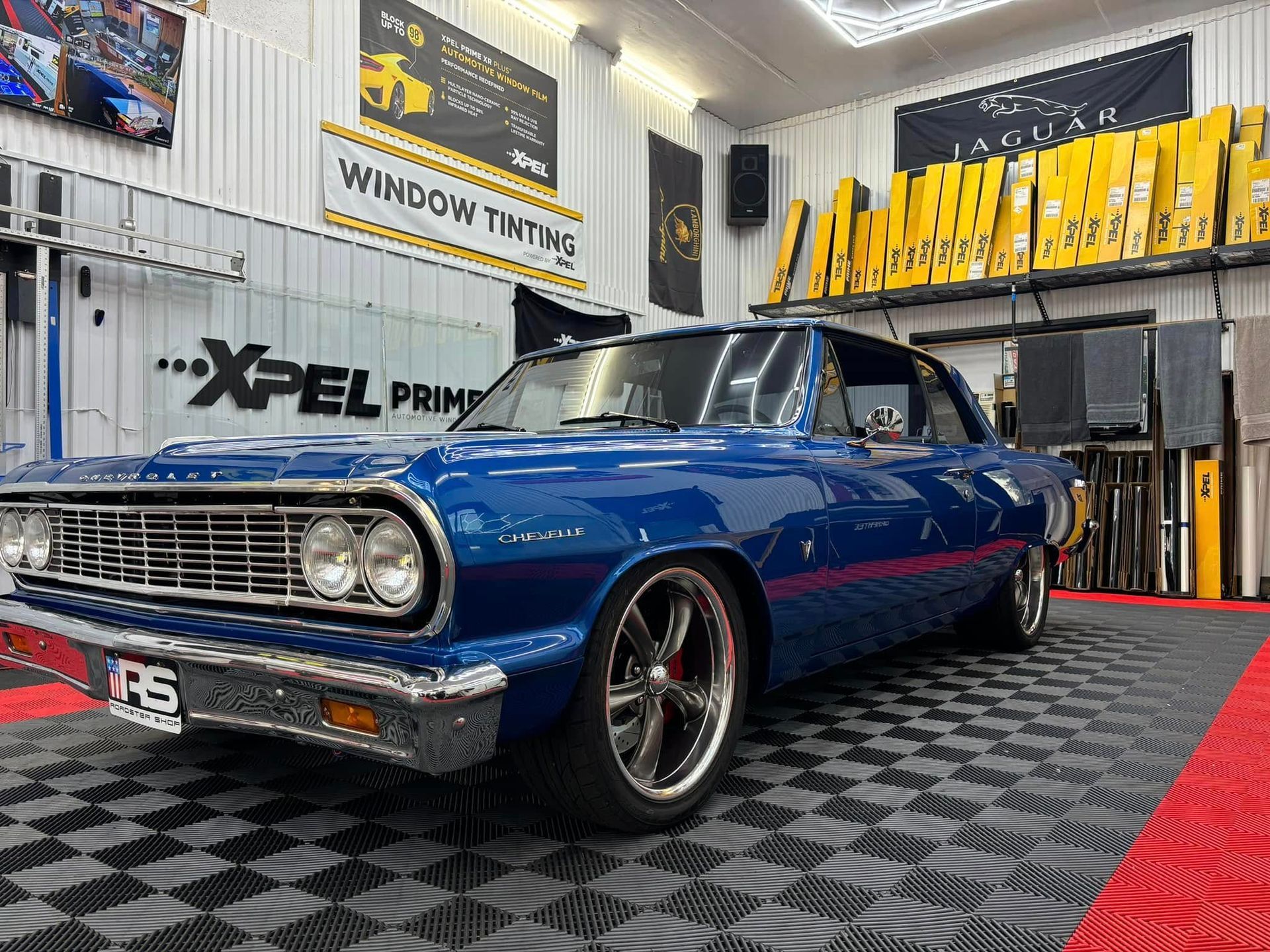 A white sports sedan parked inside a workshop with specialized floor tiles and a
