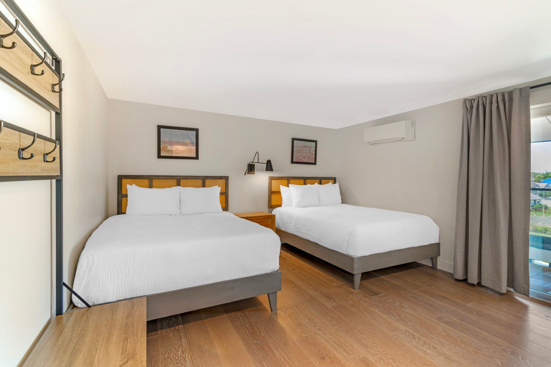 A wooden bed frame with cane paneling, white pillows, a patterned accent pillow, a framed photo, and a small potted plant.