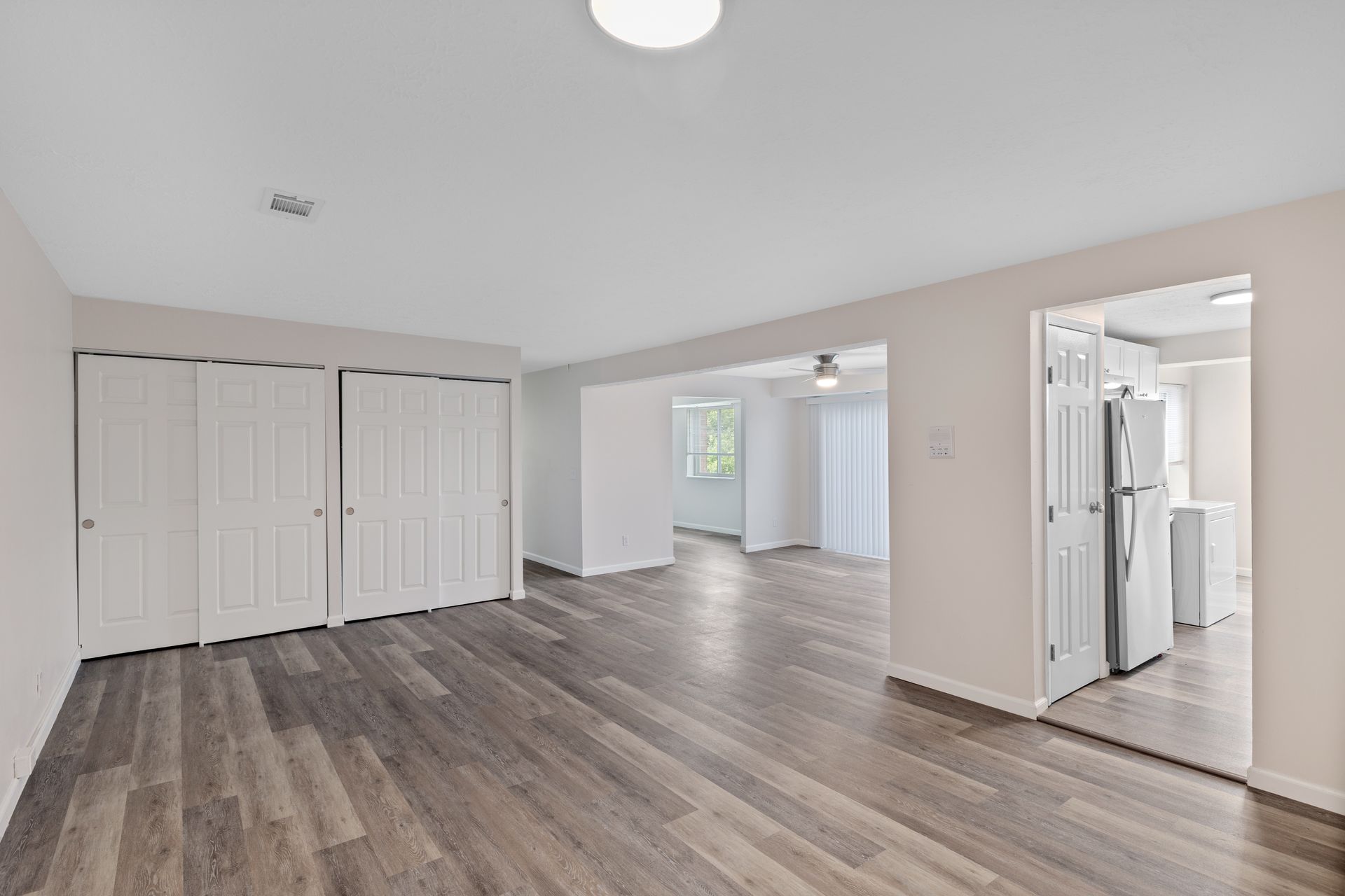 Spacious renovated apartment living area with wood-style flooring, large closets, and bright natural light.