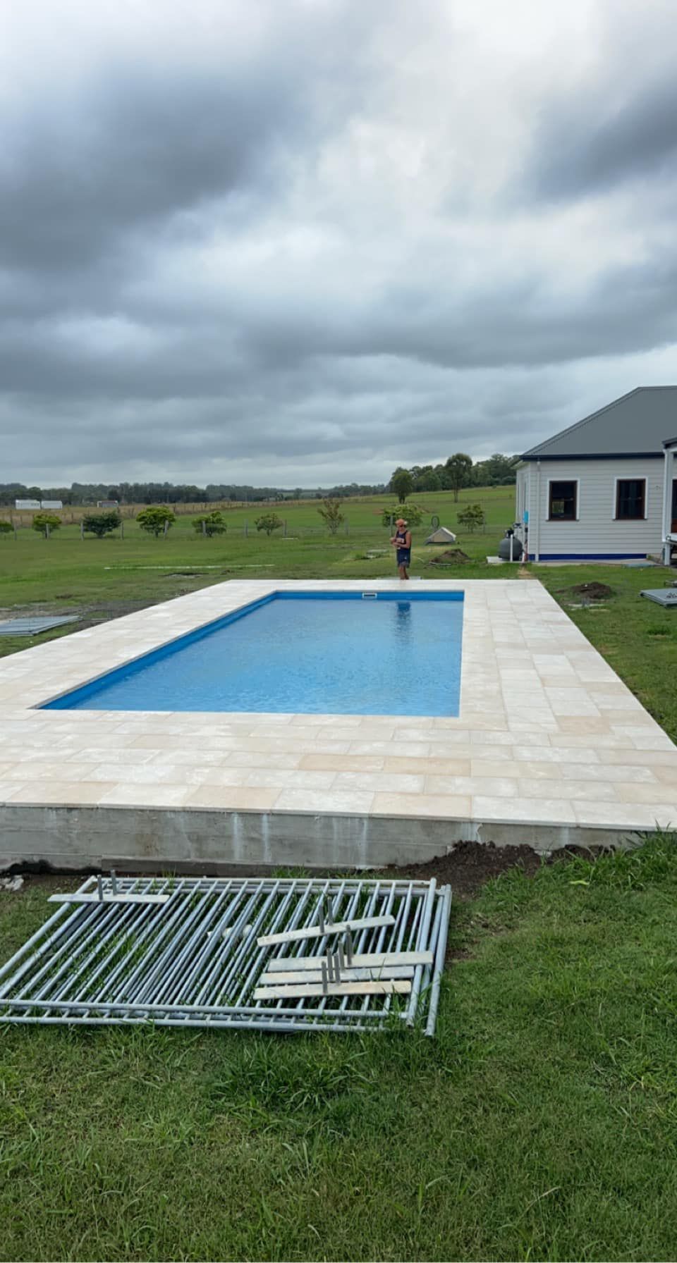 Rectangular pool with blue water and beige tile surround, overcast sky — East Coast Paving in Seaham, NSW