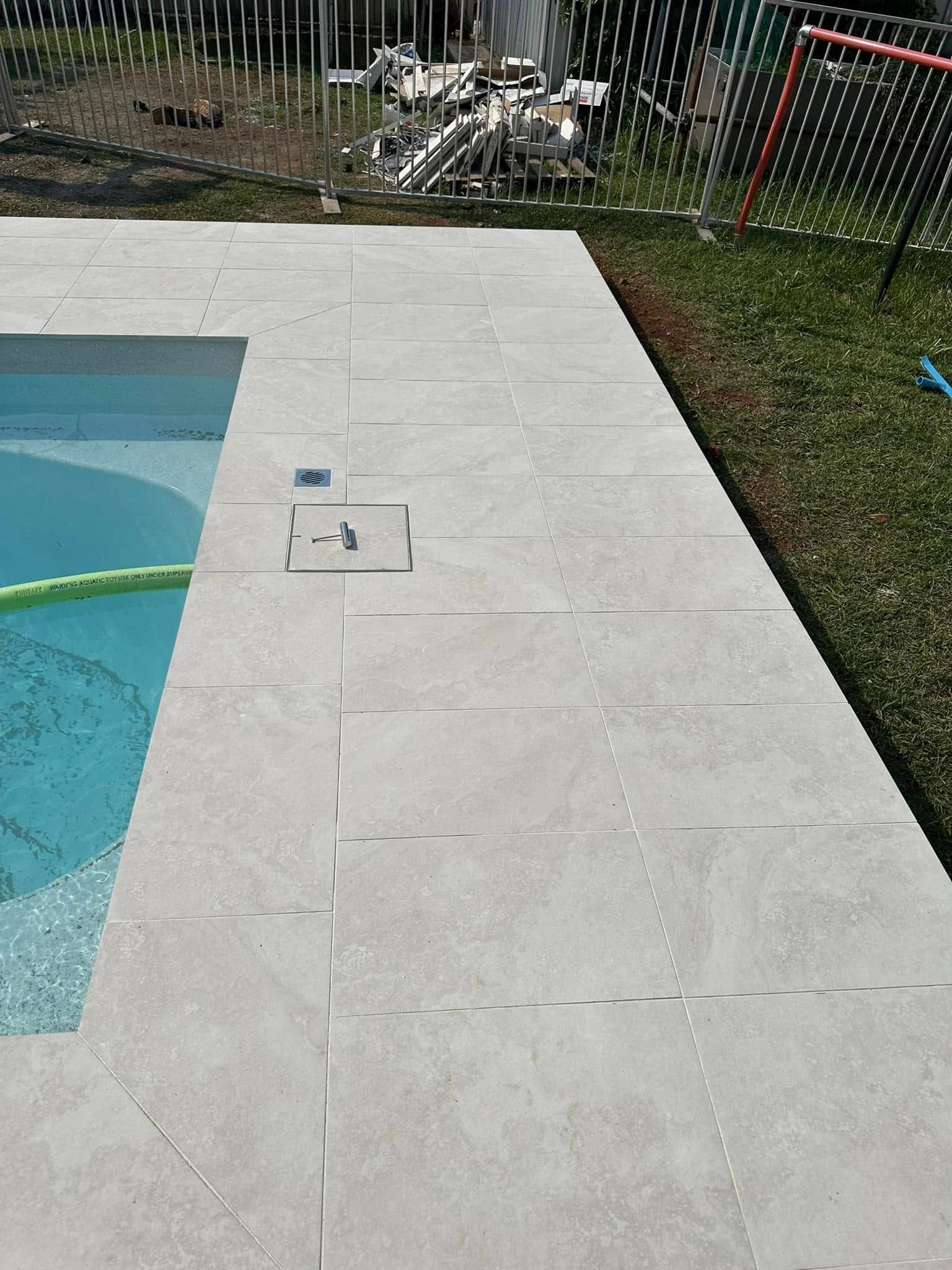 Poolside With Light Gray Tiles and Grass — East Coast Paving in Raymond Terrace, NSW
