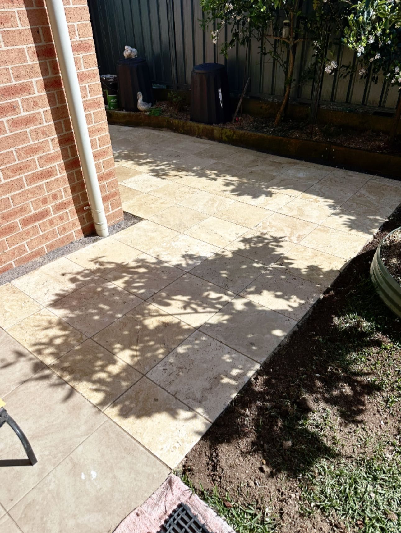 Patio Pavers Next to a Brick Wall With Tree Shadows on a Sunny Day — East Coast Paving in Raymond Terrace, NSW