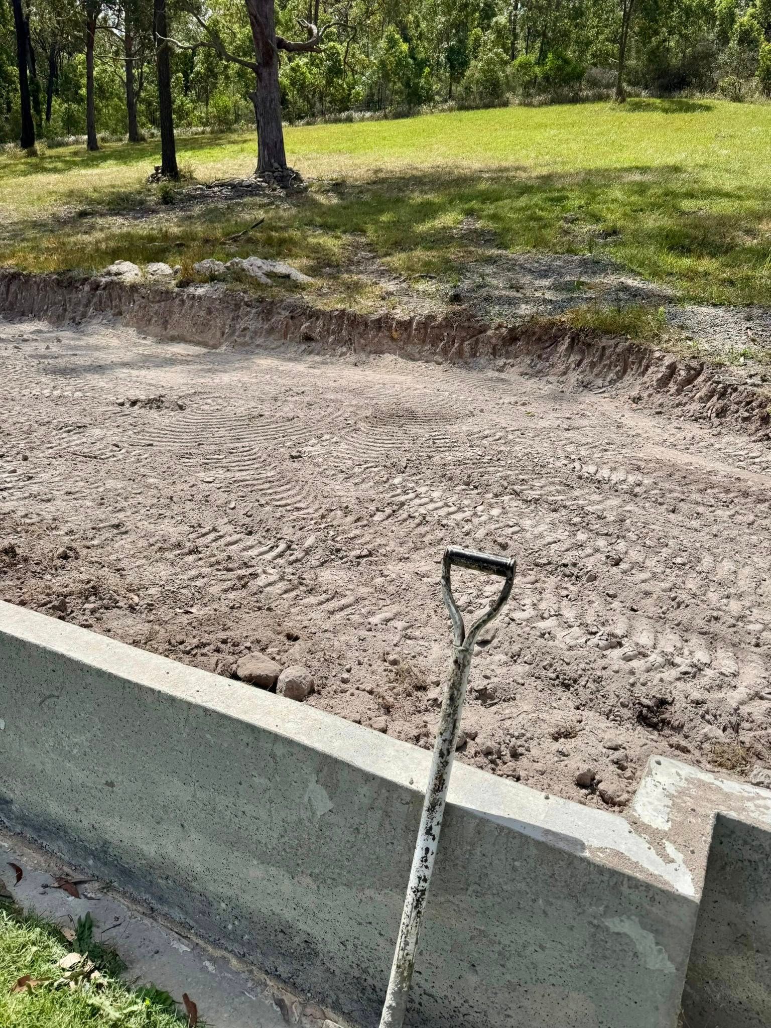 Shovel rests on concrete steps near a dirt clearing, likely for a landscaping project — East Coast Paving in Seaham, NSW
