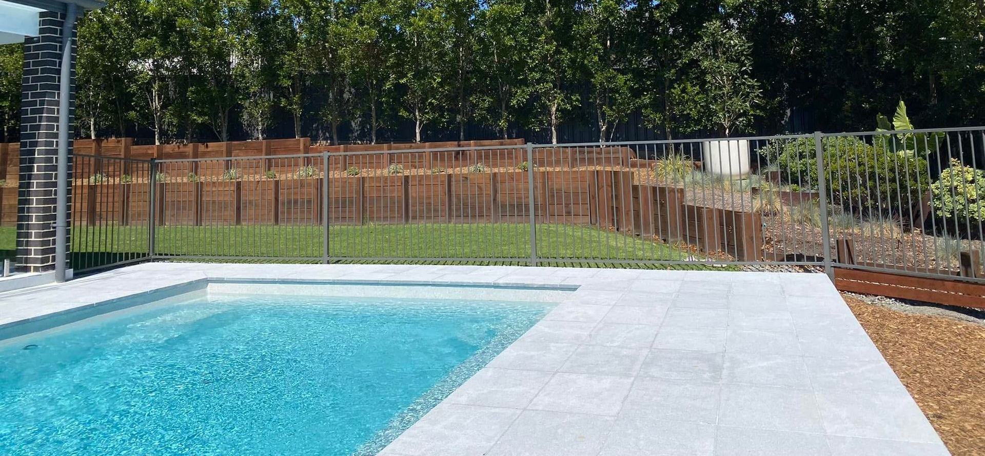 Swimming pool with a blue surface, surrounded by a gray patio and a green lawn