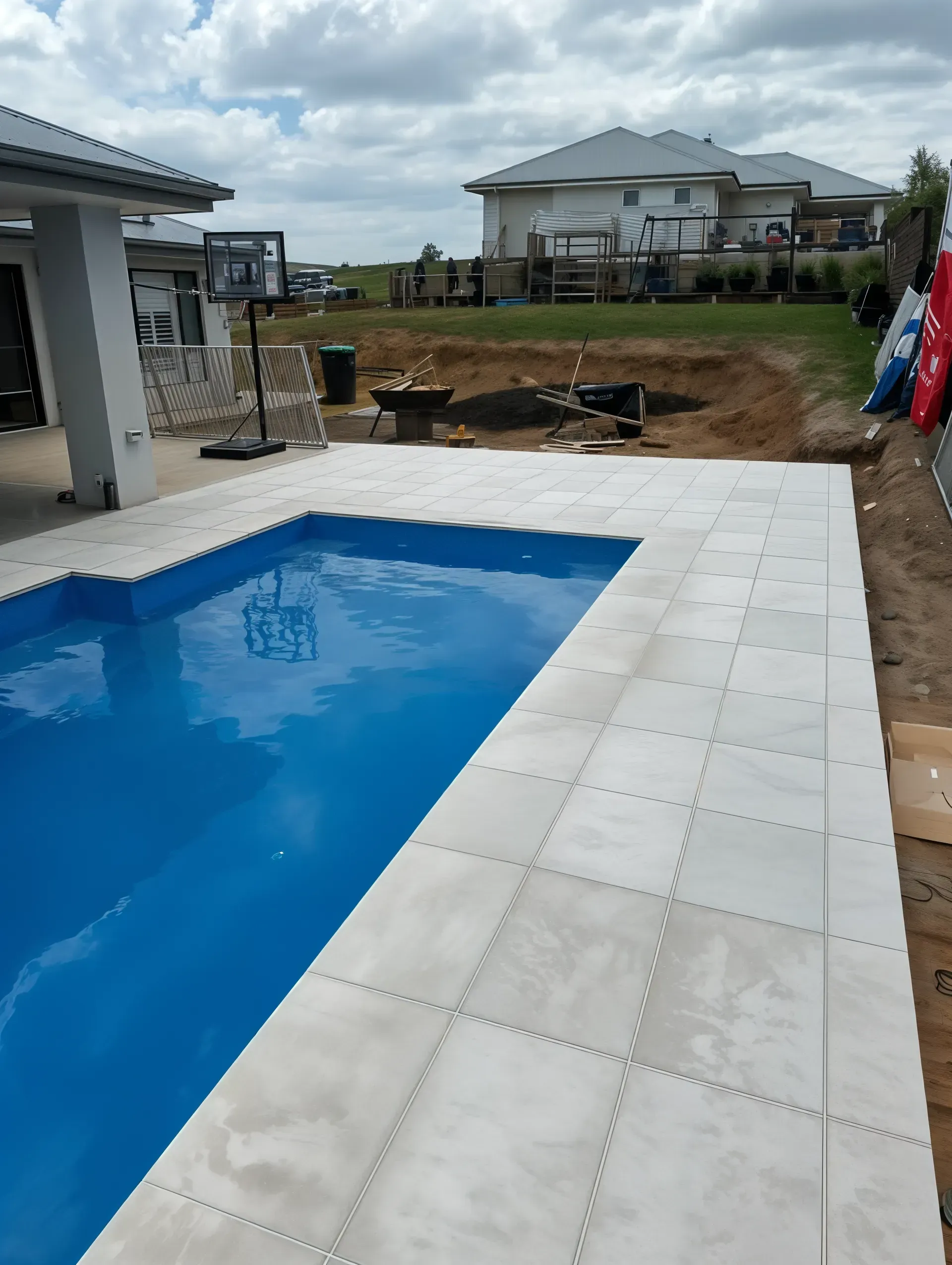 Swimming pool with light-colored tile surround; in the background — East Coast Paving in Seaham, NSW