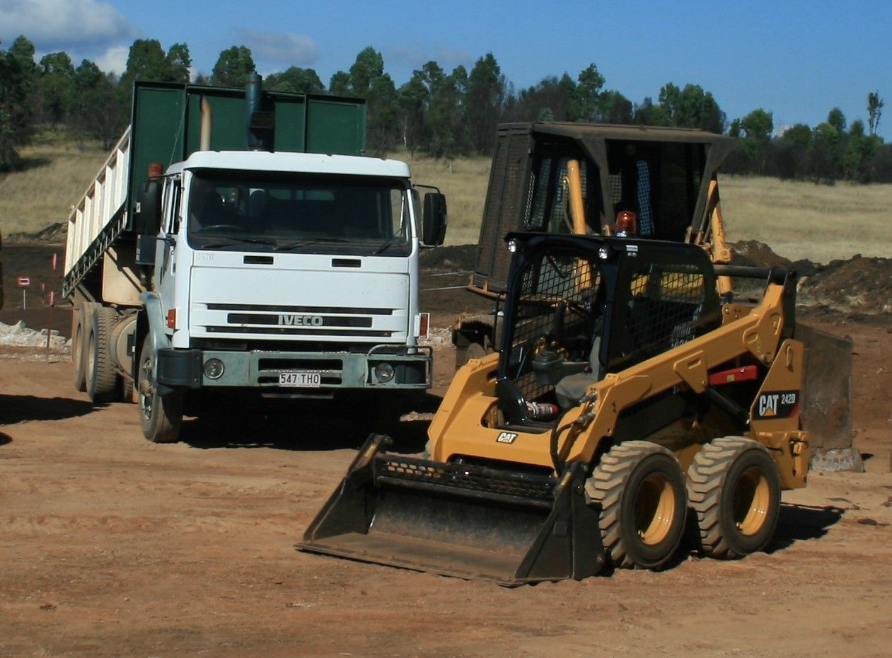 A Bobcat Next To A White Truck — Greenslade's Dozer & Excavator Hire Pty Ltd In Taabinga, QLD