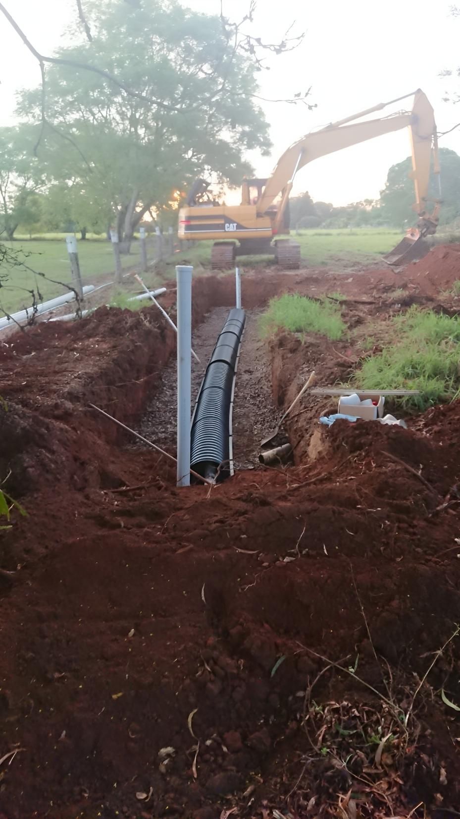 A Large Excavator Is Digging A Trench — Greenslade's Dozer & Excavator Hire Pty Ltd In Taabinga, QLD